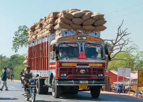 NAGAUR, INDIA - CIRCA FEBRUARY 2011: Overloaded dump truck filled with jute bags on the road.