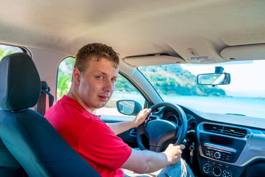 Young man driving his car near the sea