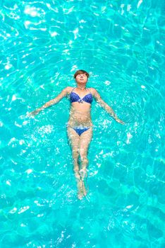 young girl floating in the pool outdoors