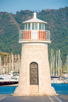 beautiful lighthouse on the background of mountains and moored yachts