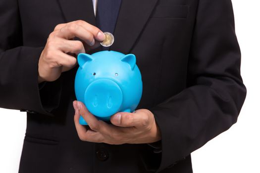 Closeup of businessman in a suit standing holding a blue piggy bank