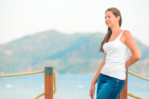 beautiful girl on the pier looks attentively aside