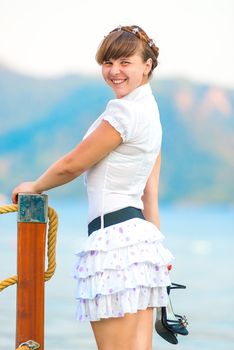 cheerful girl with shoes in hand on the pier