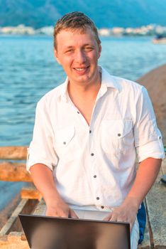 a young man with a laptop on the pier