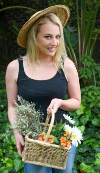 Lovely blond lady with a basket full of flowers from the garden