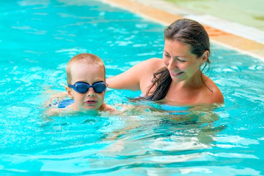 Mom teaches son to swim in the pool