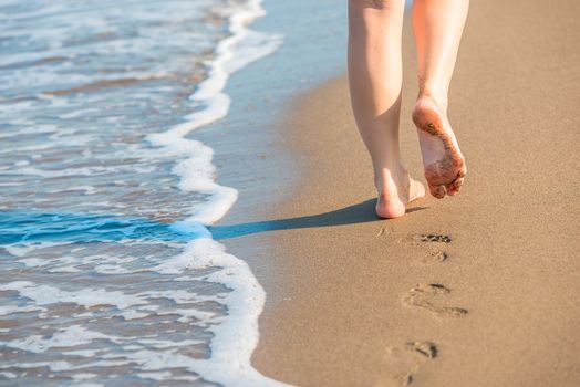 shapely female legs leave footprints on a sandy beach