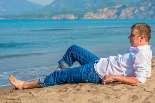 male businessman lying on the beach near the sea