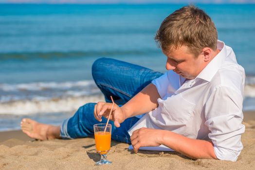 successful young man resting by the sea with cocktail