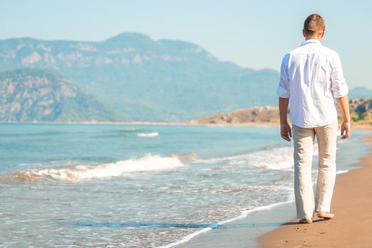 male walking barefoot on the beach at the resort