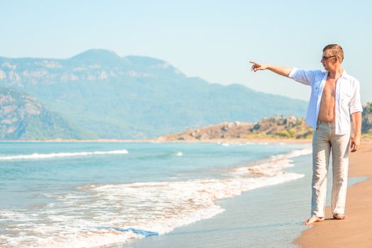 young man on the beach shows seaward