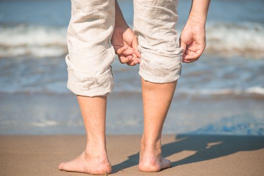male tucks linen trousers on the beach