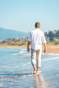 successful young man walking along a sandy beach