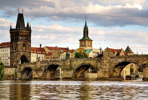 Photo shows the bridge, river and some old houses in Prague.