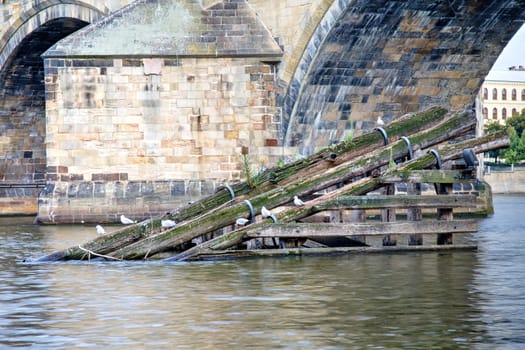 Photo shows the bridge, river and some old houses in Prague.