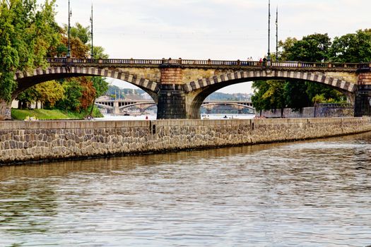 Photo shows the bridge, river and some old houses in Prague.