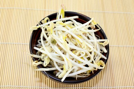 a bowl of mung bean sprouts on a bast mat