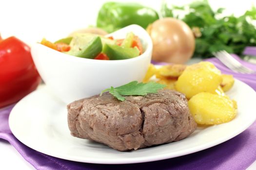 Ostrich steaks with baked potatoes and parsley on bright background