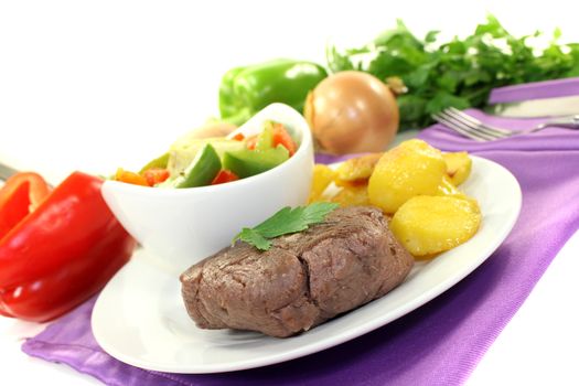 roasted ostrich steaks with baked potatoes on bright background