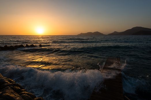 Red sky over a rocky seashore. Sunset landscape with high waves