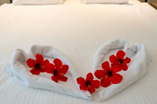 heart made from towels with flowers on honeymoon bed