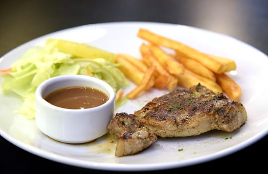 Pork steak with salad in white dish