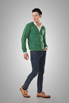 Handsome young Asian man with sweater, full length portrait isolated.