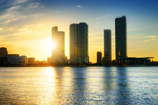 Miami city skyline panorama at dusk with urban skyscrapers over sea with reflection 