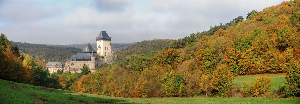 Panorama of Karlstejn Castle in beautiful autumn colored landscape with the sun
