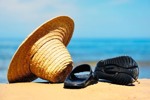 Wicker hat and rubber sandals on the sandy beach