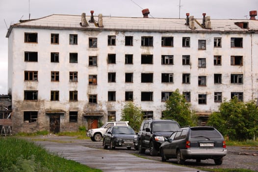 Cars near abandoned tower block house, Magadan region, Seimchan, Russia