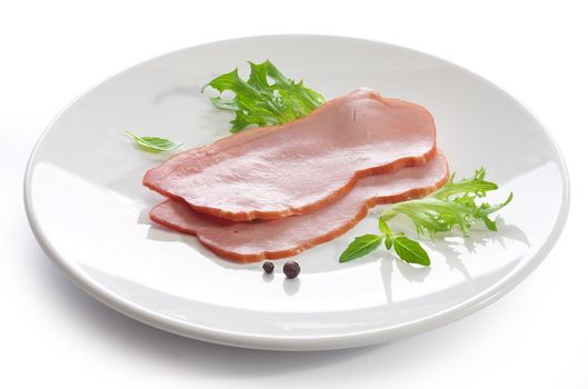 Two pieces of pork loin with fresh green lettuce and basil on the white plate