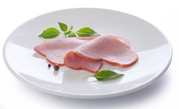 Two pieces of pork loin with fresh green lettuce and basil on the white plate