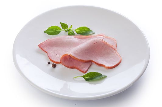 Two pieces of pork loin with fresh green basil on the white plate