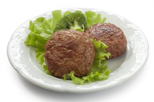 Two meat rissoles with fresn green lettuce and broccoli on the white plate