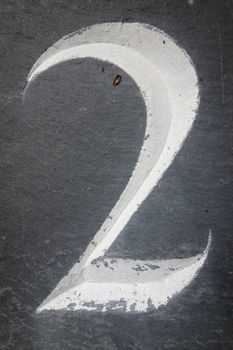 White painted number two carved into grey slate