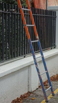 Blue and orange ladder leaning against a building