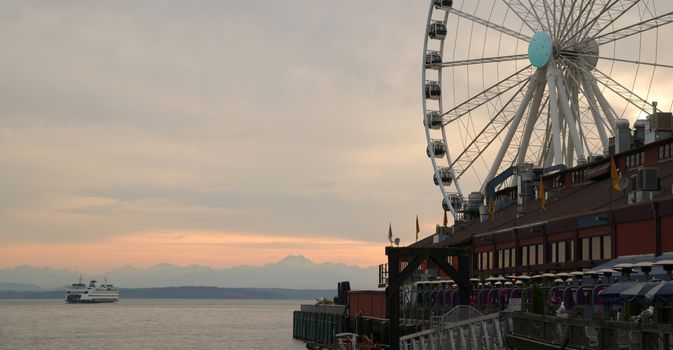 The sun has already set as a ferry heads out to Bainbridge Island the Olympic Range in background