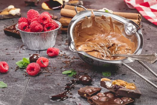 A bowl of melted chocolate with raspberries for dipping. Preparing food. Cooking concept . Done with a vintage retro filter. Macro, selective focus