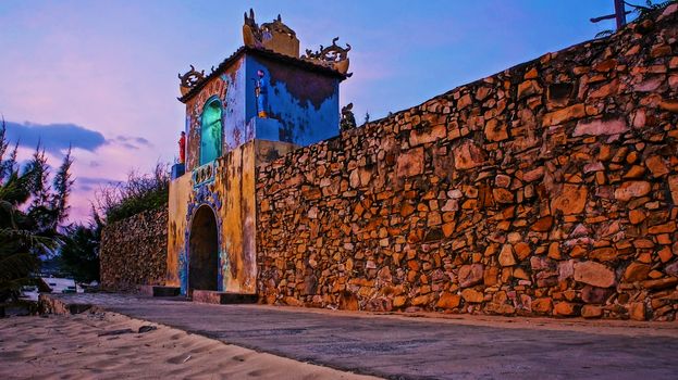 BINH THUAN, VIET NAM- JAN 21: Impression sunrise sky at ancient temple gate, the temple with long stone wall, antique architecture of spirit place, Vietnam, Jan 21, 2014
