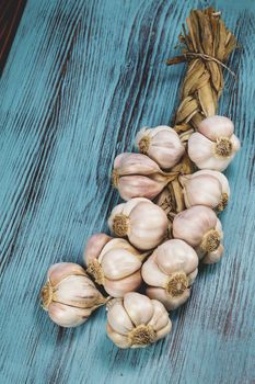 String of garlic bulbs on rustic wooden background. Done with a vintage retro filter. Macro, selective focus