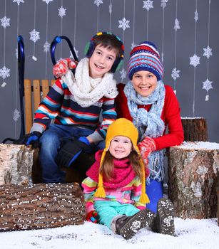 Winter Fashion. Adorable happy boy and girls in winter hat, gloves and sweater in studio.