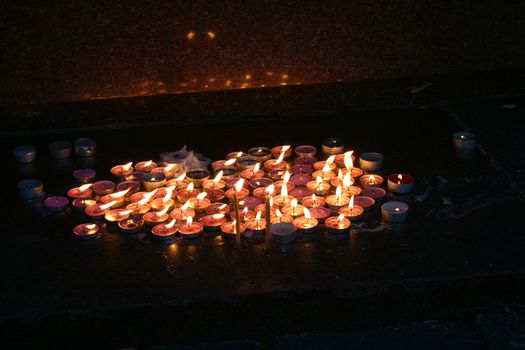 The group lit memorial candles in the dark with reflection in stone