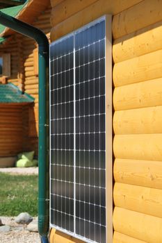 Solar battery on the yellow wall of a wooden house