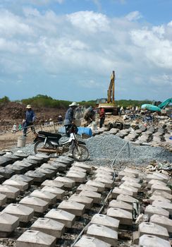 MEKONG DELTA, VIETNAM- JULY 8: Asia worker working at  breakwater construction site, bulldozer, excavator, concrete mixer, building materials for project, people work hard, Viet Nam, July 8, 2014