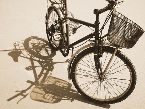 Old bike reflect on sand surface under sunshine on day