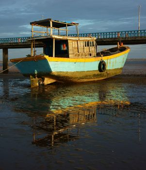 Harmony landscape of colorful view, wooden fishing boat reflect shadow on water, tide going out let black sand and hold of boat, cloud sky, brilliant color and amazing reflection