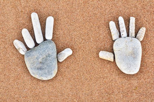 Hands patterns of pebbles on the sandy beach