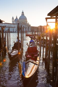Venice, Italy - October 31, 2014: Traditional wooden boads and a gondolier in the Grand Canal in front of Santa Maria della Salute in sunset.
