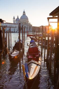 Venice, Italy - October 31, 2014: Traditional wooden boads and a gondolier in the Grand Canal in front of Santa Maria della Salute in sunset.